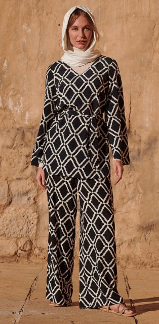 A woman wearing a black geometric blouse and palazzo trousers co-ord