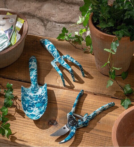 A selection of blue floral gardening tools on a wooden bench