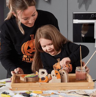 A mum and daughter doing Halloween arts and crafts in matching pumpkin sweatshirts.