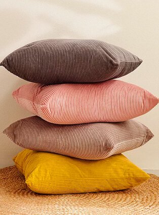 Stack of brown, pink, nude and yellow textured scatter cushions.
