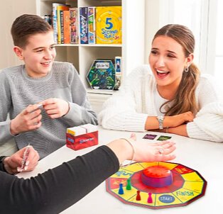 Woman and boy sit at table laughing as they play a game.