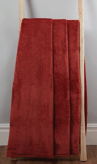 A red fleece throw draped on a wooden ladder