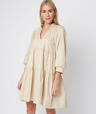 Woman wearing a V-neck beige dress with pleats