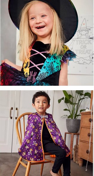 Child wearing witches hat and colourful halloween costume. Child sitting on a chair wearing black jeans, black t-shirt and a printed purple and orange cape.