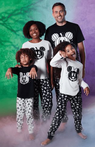 A family of four wearing coordinated Halloween Mickey Mouse pyjamas.
