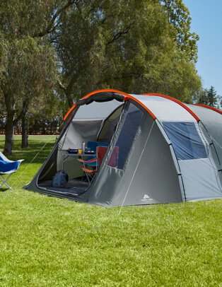 A grey and orange tent with orange and blue folding chairs