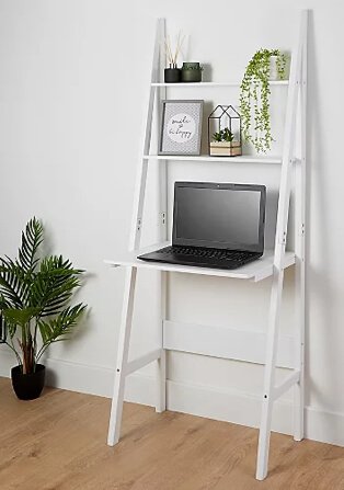 White ladder desk with green diffuser set, artificial plant, 'be happy' print, artificial plant in wire house and open laptop.