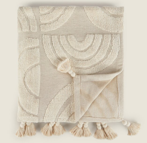 Beige rainbow throw with tassels.