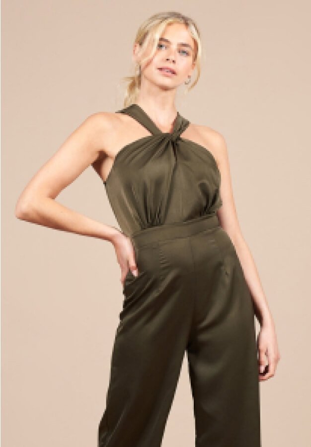 A woman posing in an olive green jumpsuit.