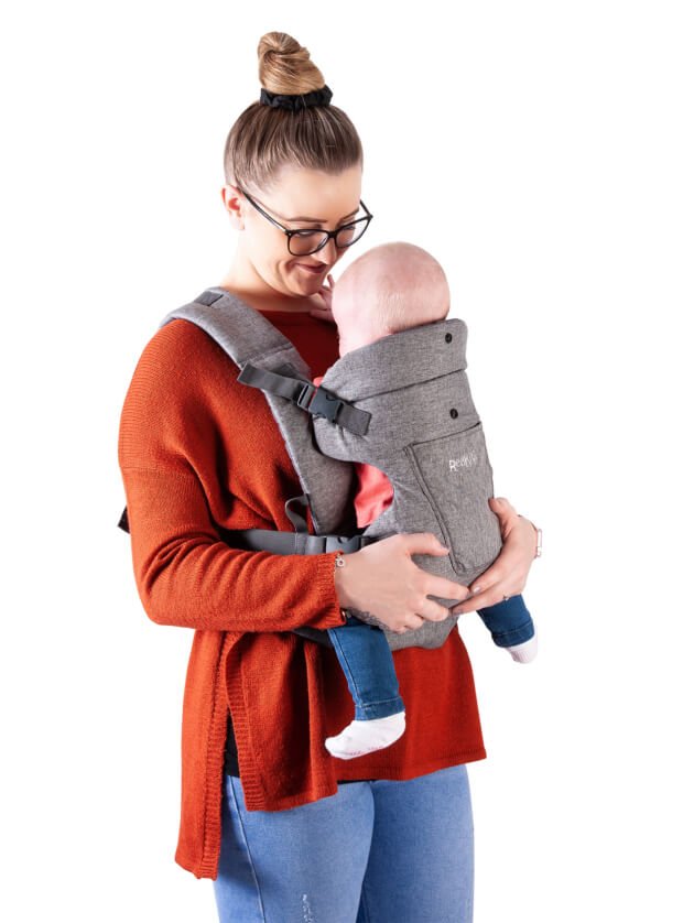 A mum wearing jeans and a red jumper holding her baby in a Red Kite Embrace Carrier.