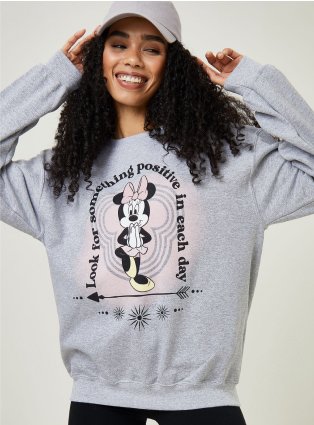 Woman poses wearing grey Disney Minnie Mouse hoodie and grey baseball cap.