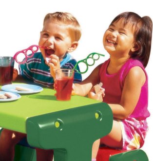 Three kids having snacks on a green and red plastic table