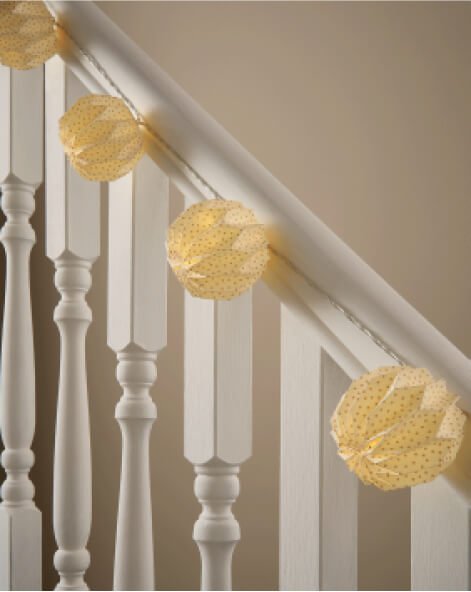 Lantern lights hanging on a stair banister.
