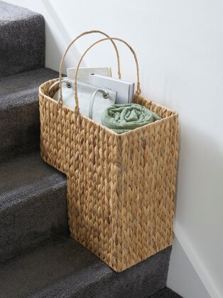 Stairs feature wicker storage basket containing a book, handbag and rolled-up blanket.
