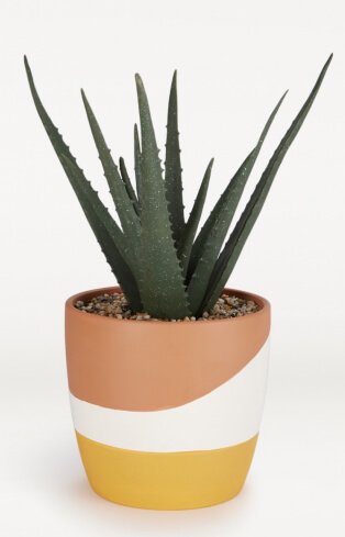 Artificial plant in orange, white and yellow striped pot.