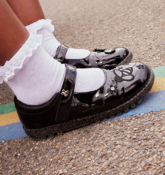 A close shot of a child wearing black patent school shoes and white frilly socks.