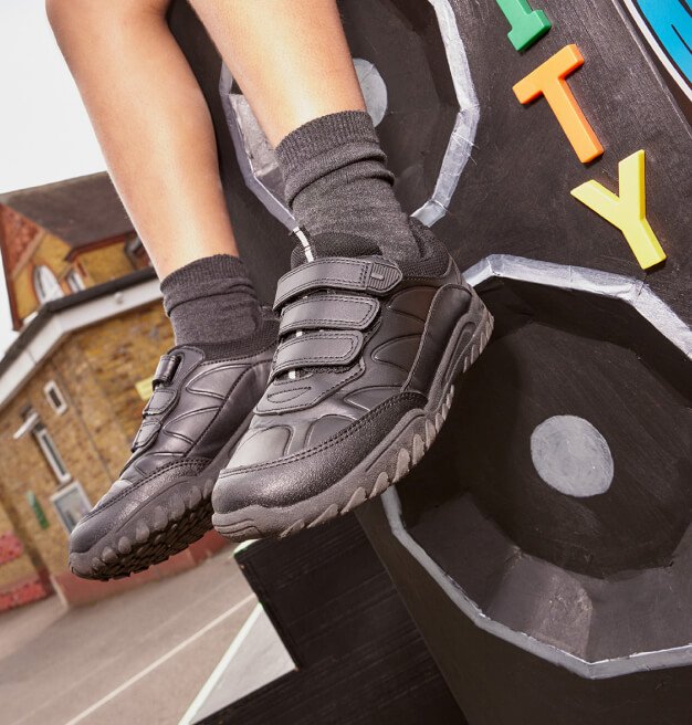 A close shot of a child wearing black three-strap school shoes.