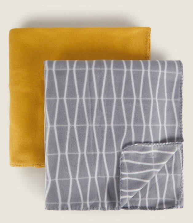 A geometric grey blanket folded on top of a yellow blanket.