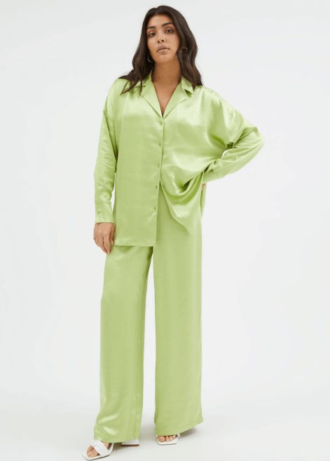 A woman posing in a green satin shirt and trousers co-ord