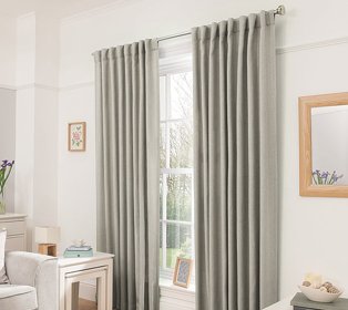 Sage green curtains hanging from silver rail in a decorated white room