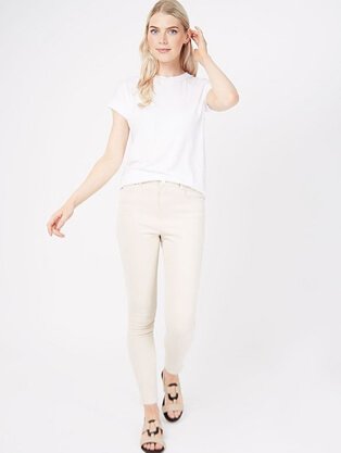 Woman wearing a white t-shirt with cream lightwash skinny jeans and strappy sandals