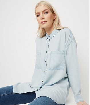 Woman wearing a light wash denim longline shirt with dark wash jeans