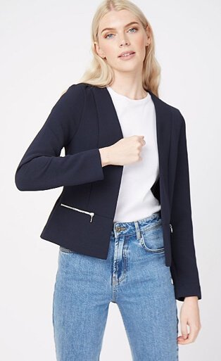 Woman wearing a white t-shirt, navy zip detail blazer and mid wash jeans
