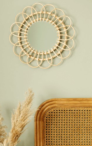 A wicker headboard, natural hand woven willow mirror and pampa grass on a cream wall.