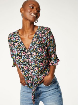 Woman wearing floral top and jeans.