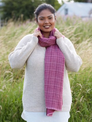 Woman wearing cream knitted jumper and a pink check scarf.