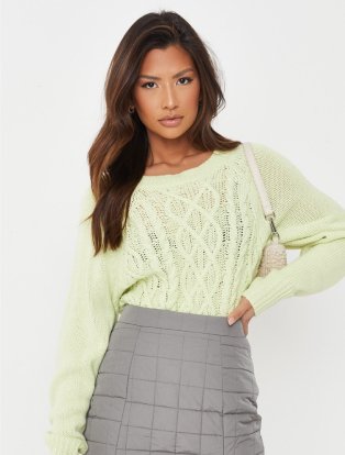 Woman wearing light green knit jumper and grey chequered mini skirt.