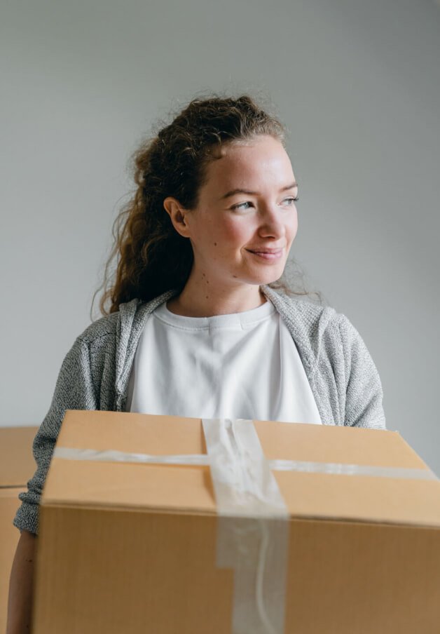 A smiling woman holding a brown box.