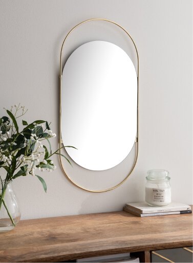 A gold-toned lozenge mirror on a wall.