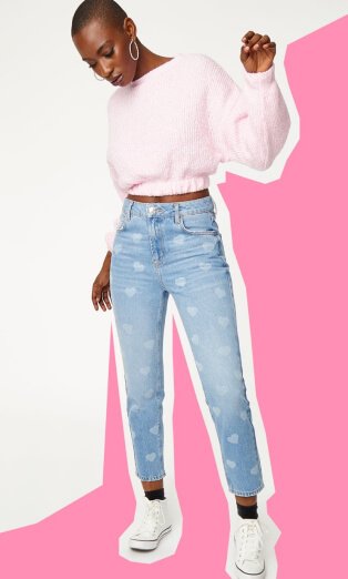 Woman wearing cropped pink fluffy jumper and heart print jeans.