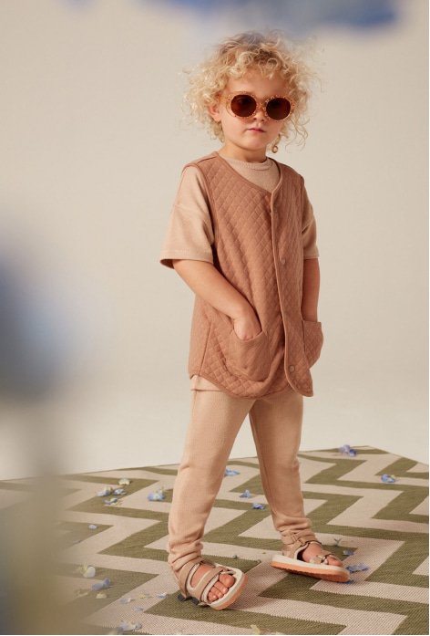 A child wearing a unisex outfit and sandals.