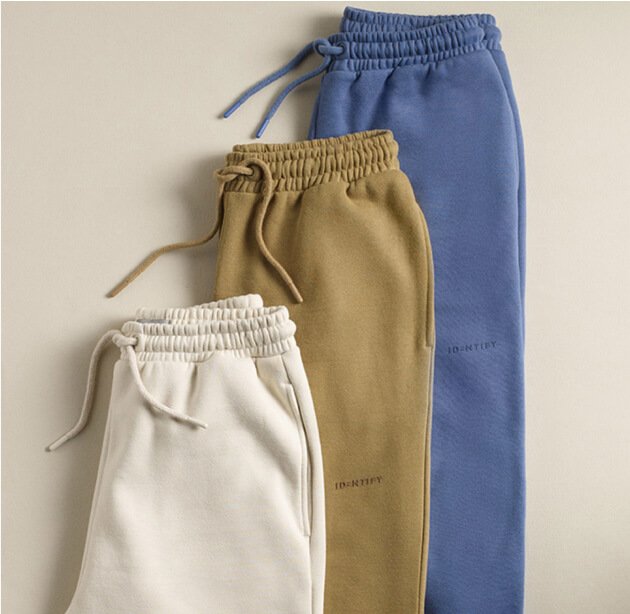 Three different coloured joggers laid out on a cream background.