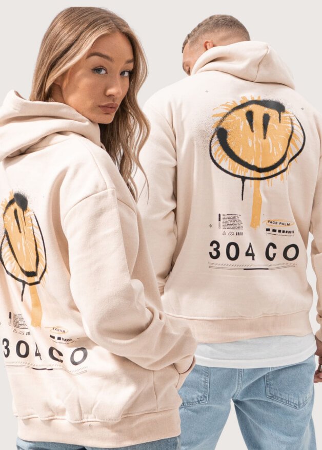 A man and woman posing in matching 304 unisex vanilla facepalm hoodies.