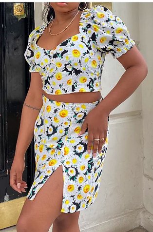 Woman poses with hand on hip wearing white, blue and yellow floral print puff sleeve crop top and matching slit detail skirt.