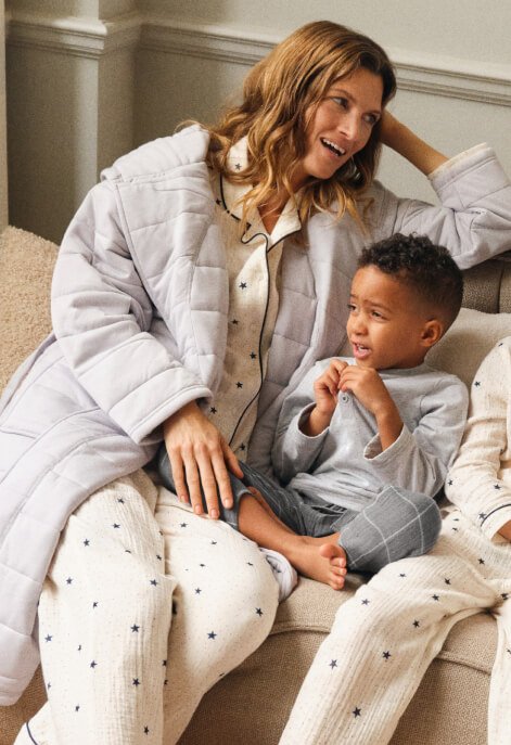 Woman wearing a grey dressing gown with cream spotty pyjamas. Boy wearing grey pyjamas.