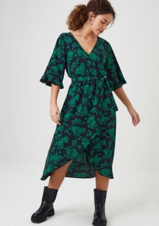 Woman wearing knee length black and green floral print dress.