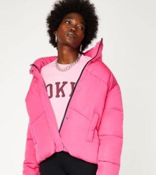 Woman wearing pink puffer jacket and pink jumper.