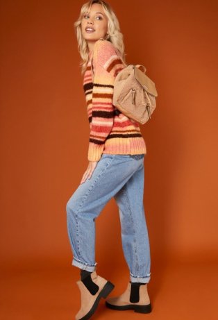 Woman wearing striped jumper, light blue jeans and brown ankle boots.