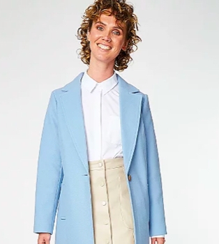 Woman poses smiling wearing white shirt, stone button down mini skirt and light blue collared longline coat.