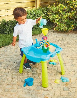 Gated garden features young boy playing with kid connection sand and water activity table.