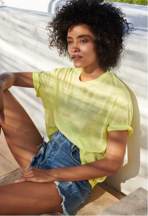 A woman wearing a lime coloured t-shirt and denim shorts.