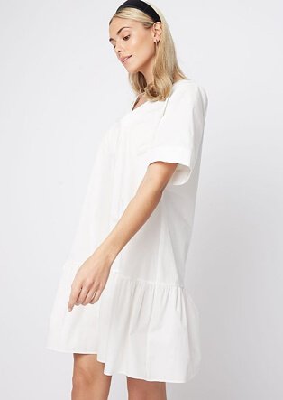 Woman wearing a white tiered smock dress with black headband