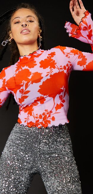 Woman wearing satin floral top and sequin trousers.