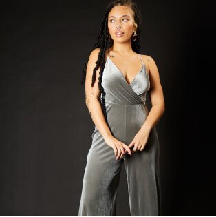 Woman wearing grey velvet jumpsuit.