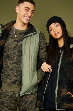 Man wearing camo matching outfit and woman wearing camo jacket.