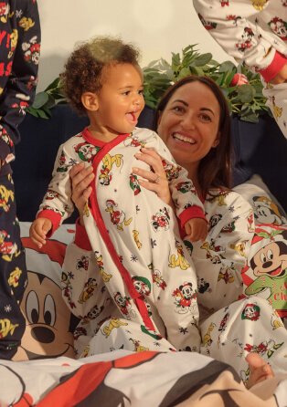 Woman holding child wearing matching Christmas Pyjamas.